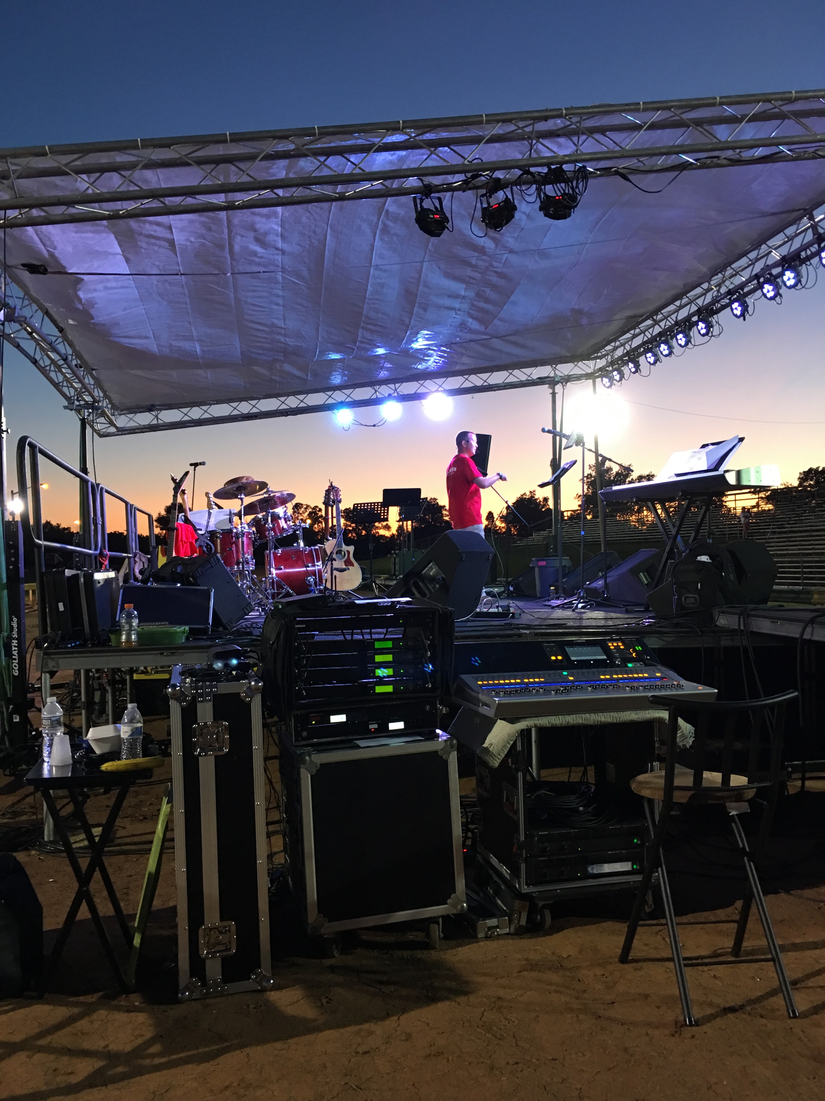 Outdoor stage setup at sunset with production gear