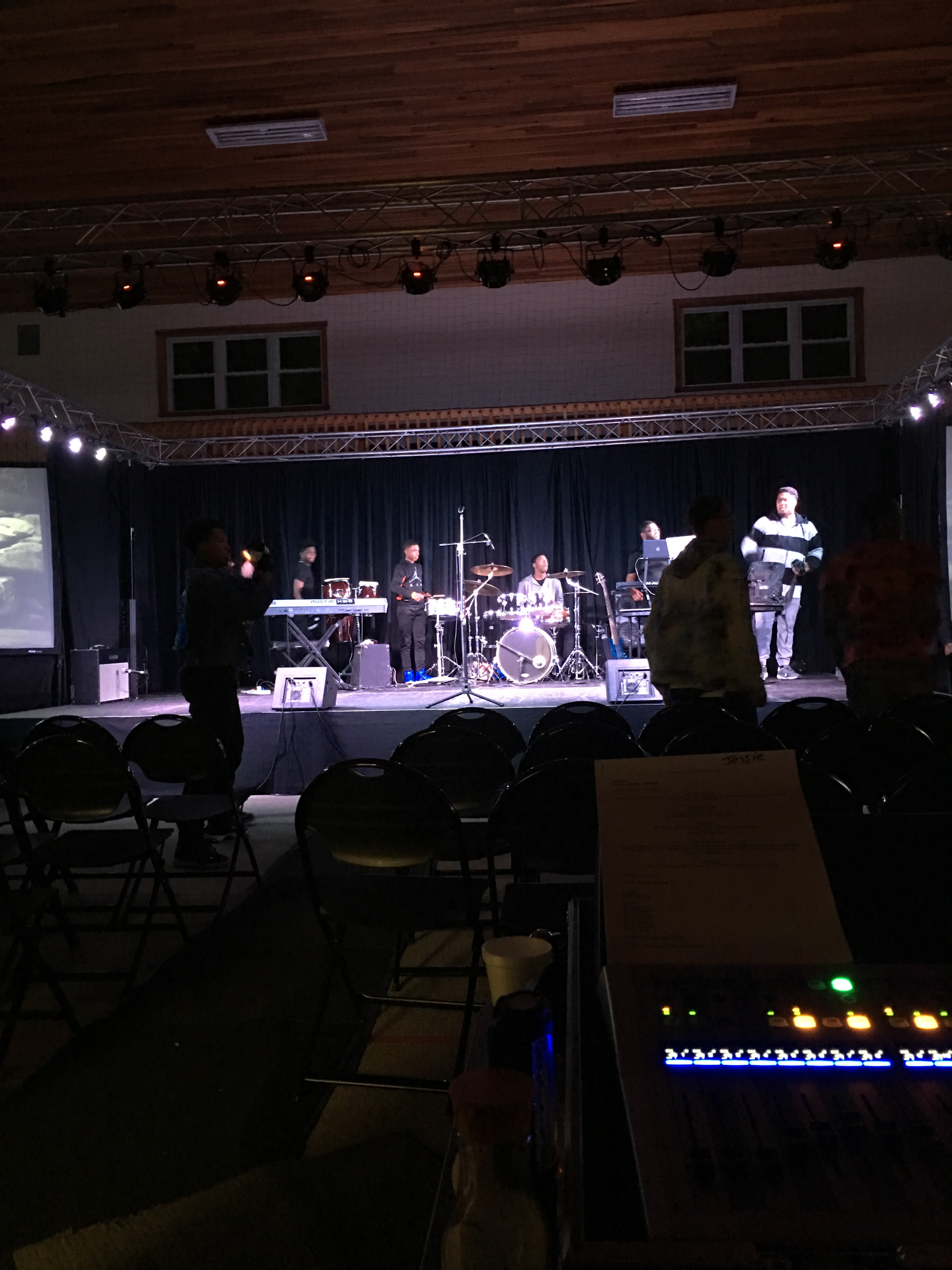 Live band performing on indoor stage with truss lighting