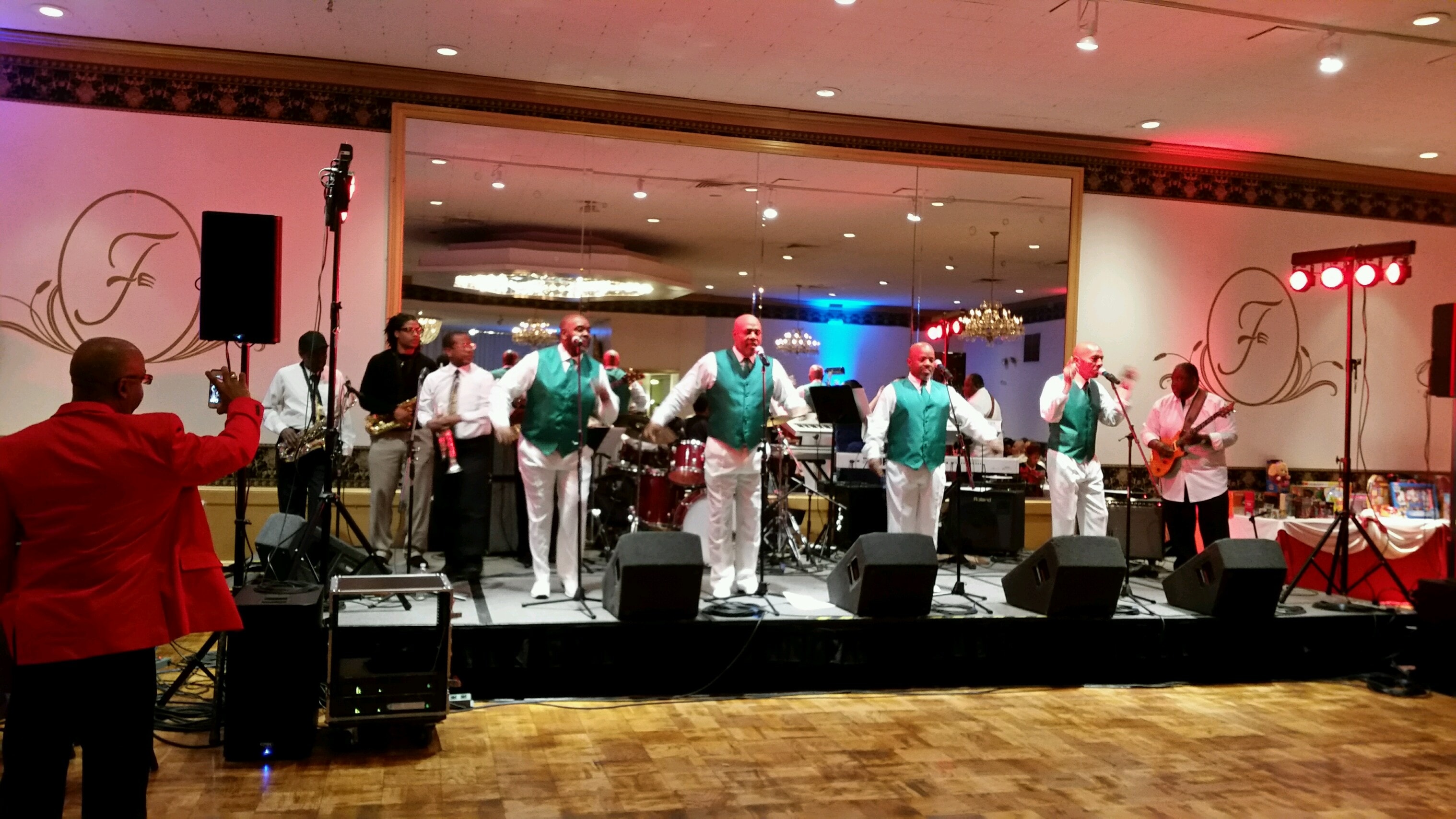 Band performing at ballroom event with teal vests