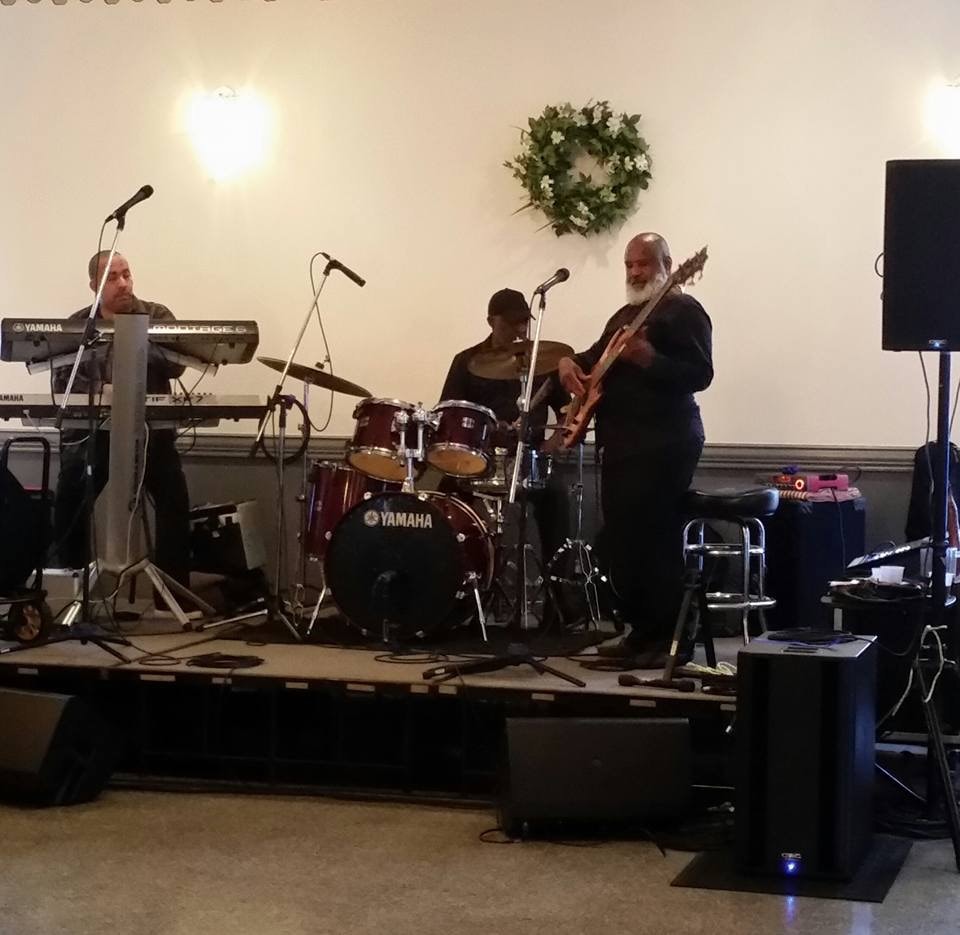 Trio performing on small indoor stage with Yamaha kit