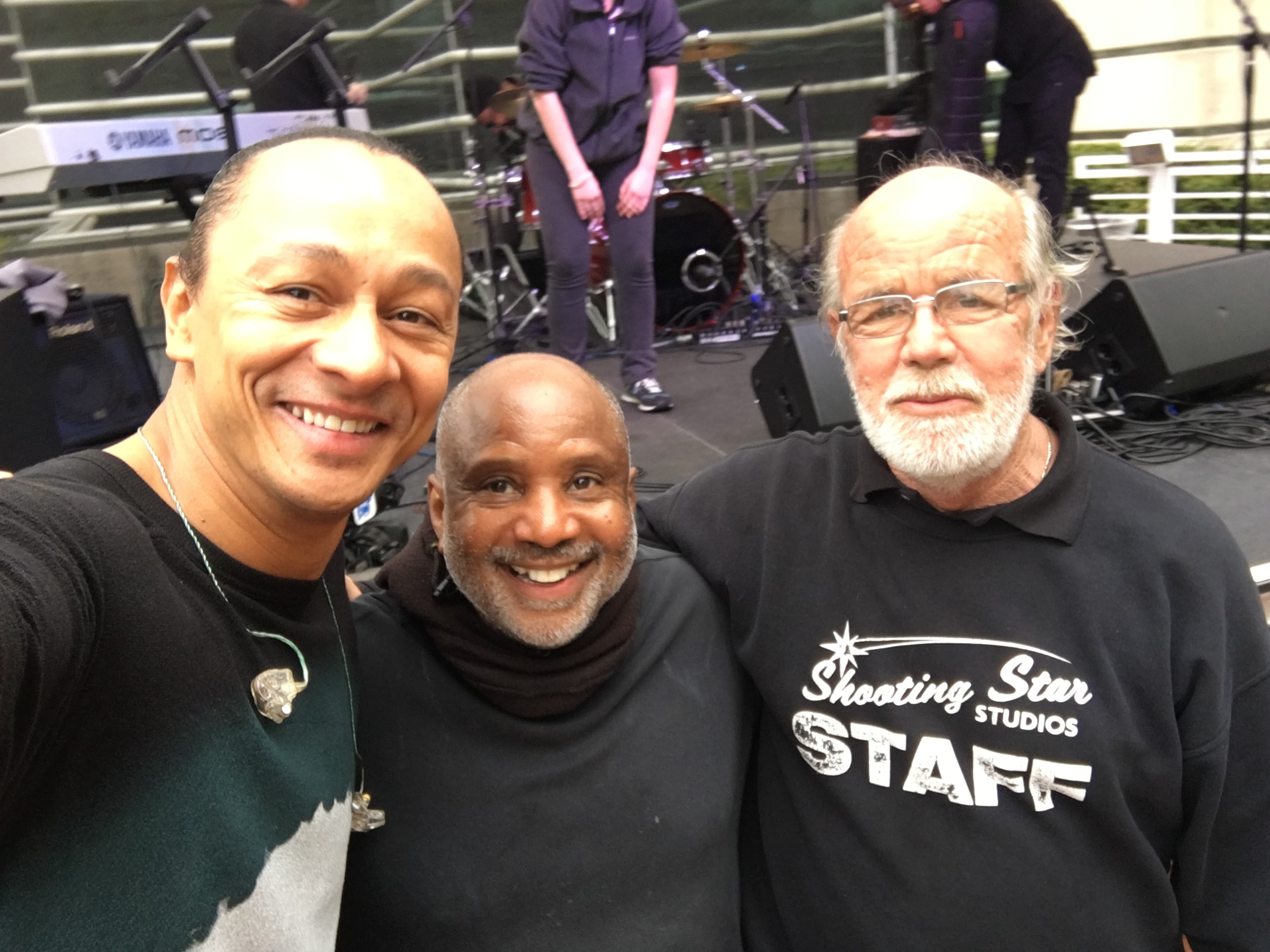 Three crew members at outdoor stage event